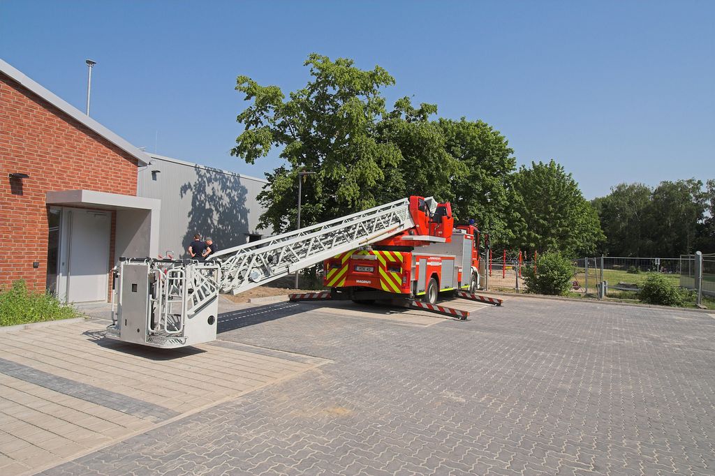 Das Foto zeigt, wie die DLK23/12 auf dem Parkplatz hinter dem Feuerwehrgerätehaus aufgestellt wird.
